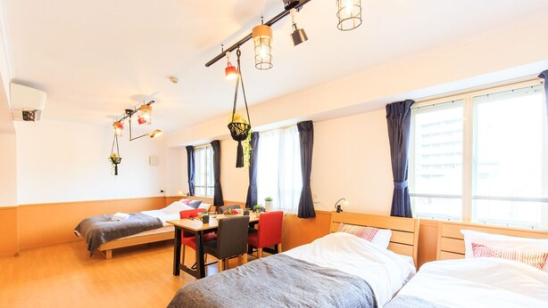 Een hotelkamer met twee eenpersoonsbedden, een eettafel, stoelen en hangplanten.