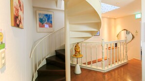 A spiral staircase with white railings and a small statue at the bottom. - Casa de Marzo (Nagoya)