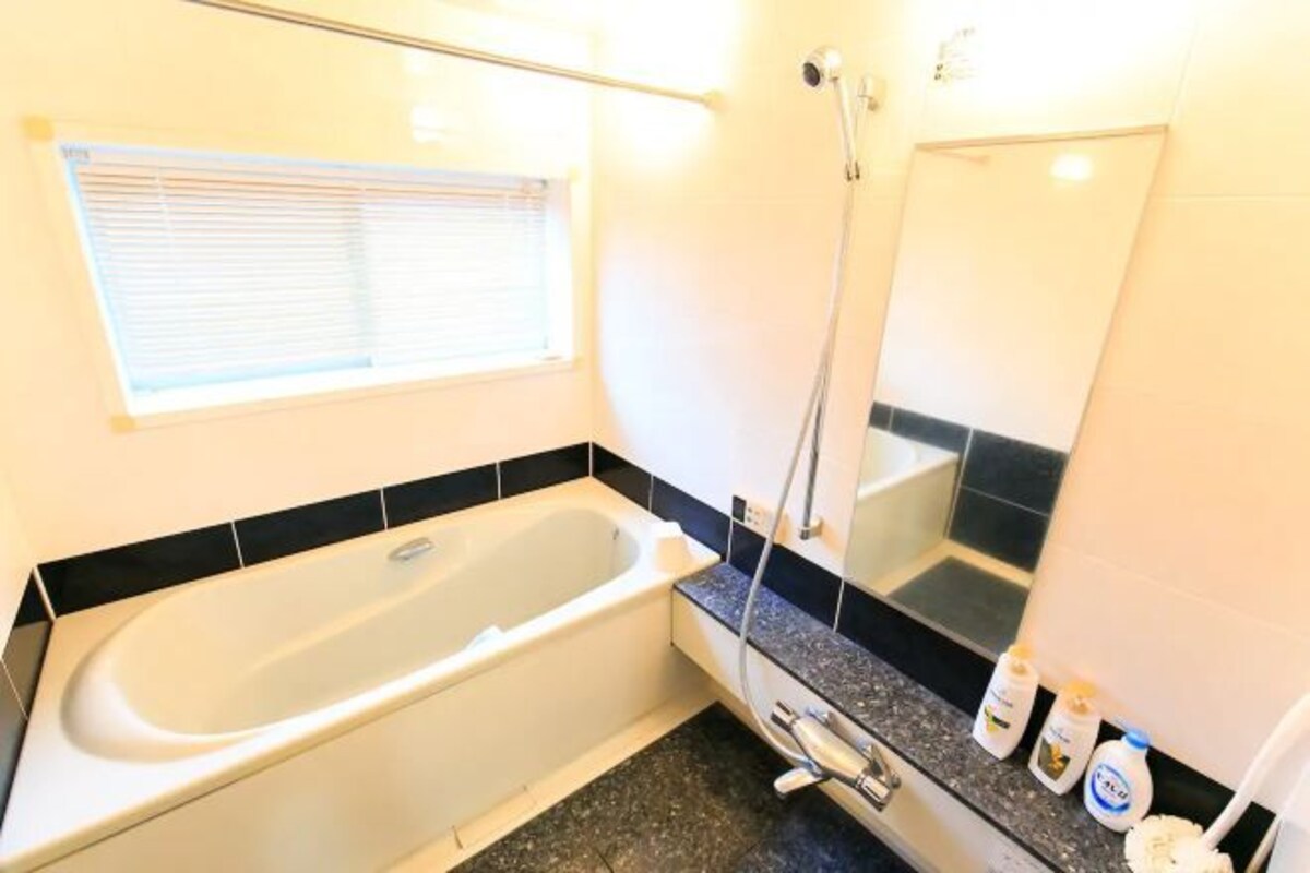 Een badkamer met een bad, douche, wastafel en spiegel.