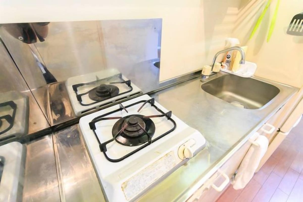 Uma cozinha com eletrodomésticos de aço inoxidável, incluindo duas bocas de fogão a gás e uma pia.