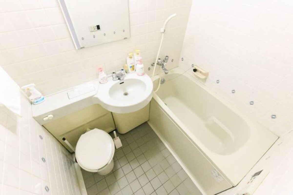 Een kleine badkamer met toilet, wastafel en bad.