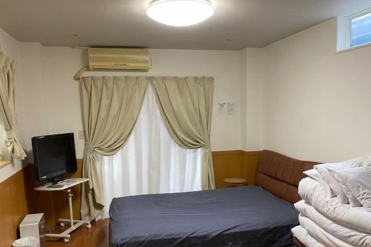 Une chambre d’hôtel équipée d’un lit, d’une télévision, de rideaux et d’un appareil de climatisation.