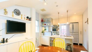 A modern kitchen with a dining table, chairs, and a TV mounted on the wall. - Casa de Marzo (Nagoya)