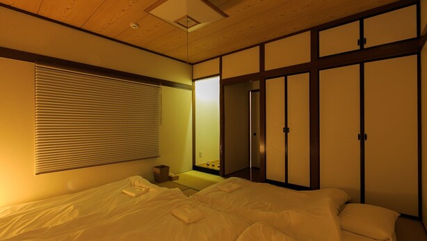 Une chambre avec un lit, une table de chevet, un miroir et des portes coulissantes.