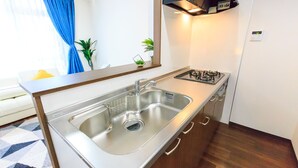 A modern kitchen with a stainless steel sink, a gas stove, and wooden cabinets. - Dai 40 prosper Apartment (Nagoya)
