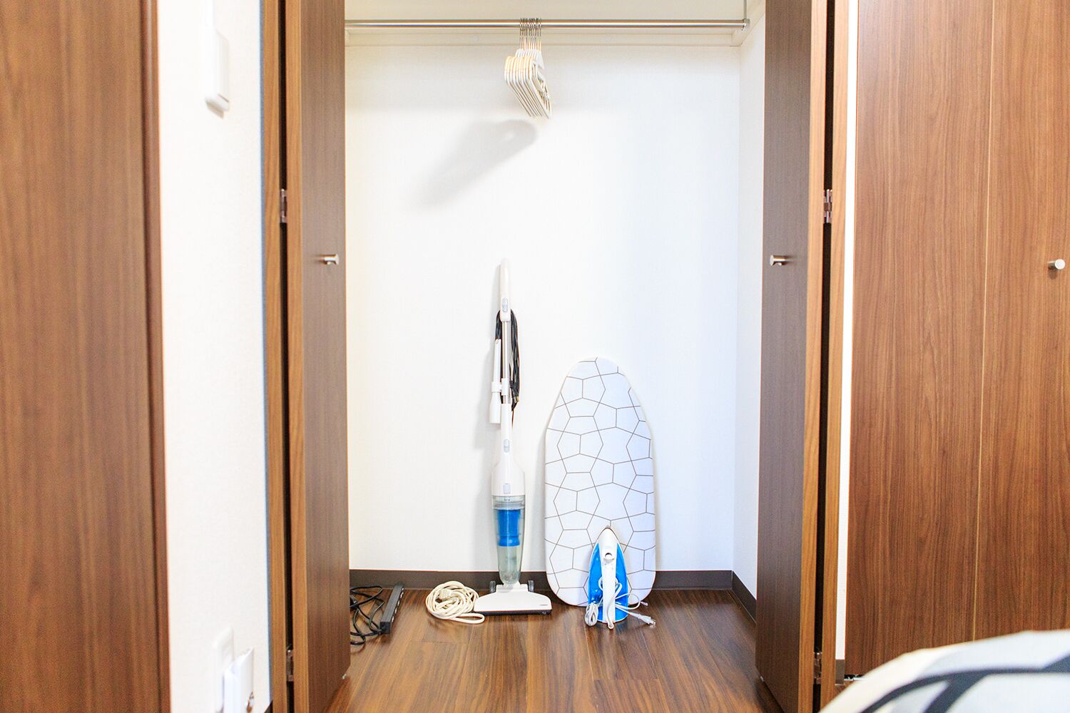 A hallway with wooden doors, a surfboard, and a vacuum cleaner.