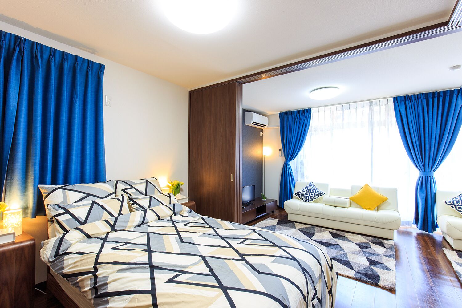 A modern hotel room with a large bed, a sofa, and a TV.