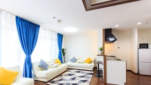 A modern living room with a sofa set, a kitchen area, and a dining table. - Dai 40 prosper Apartment (Nagoya)