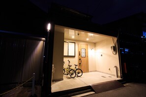 L’entrée d’un immeuble la nuit, avec un vélo garé à l’intérieur.