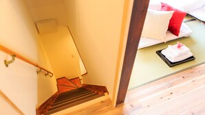 A wooden staircase leading to a room with a bed, pillows, and a tray of towels. - ORIGAMI STAY -Taishocho- (Nagoya)
