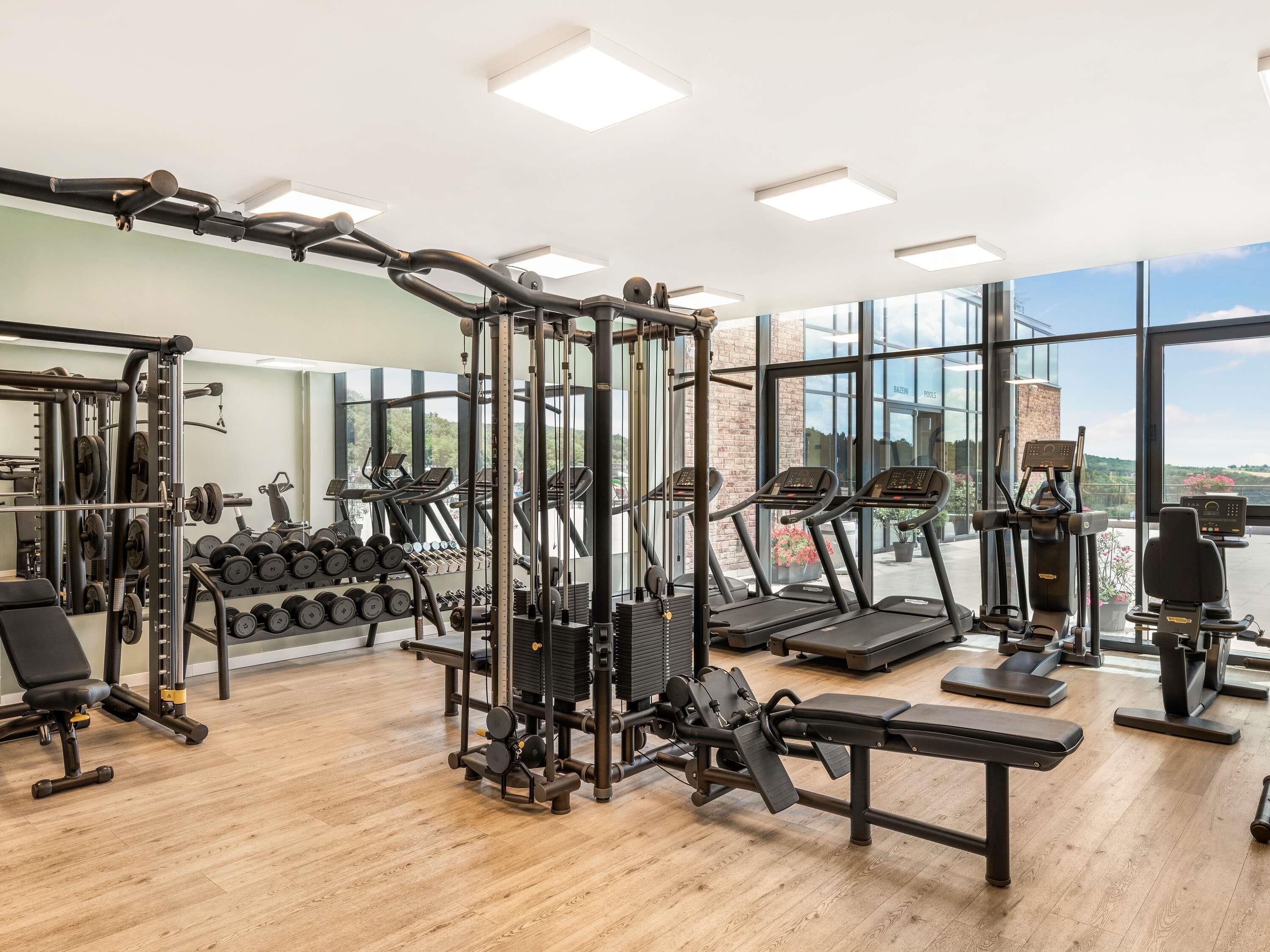 Una palestra con attrezzature cardio, macchinari per pesi e manubri.