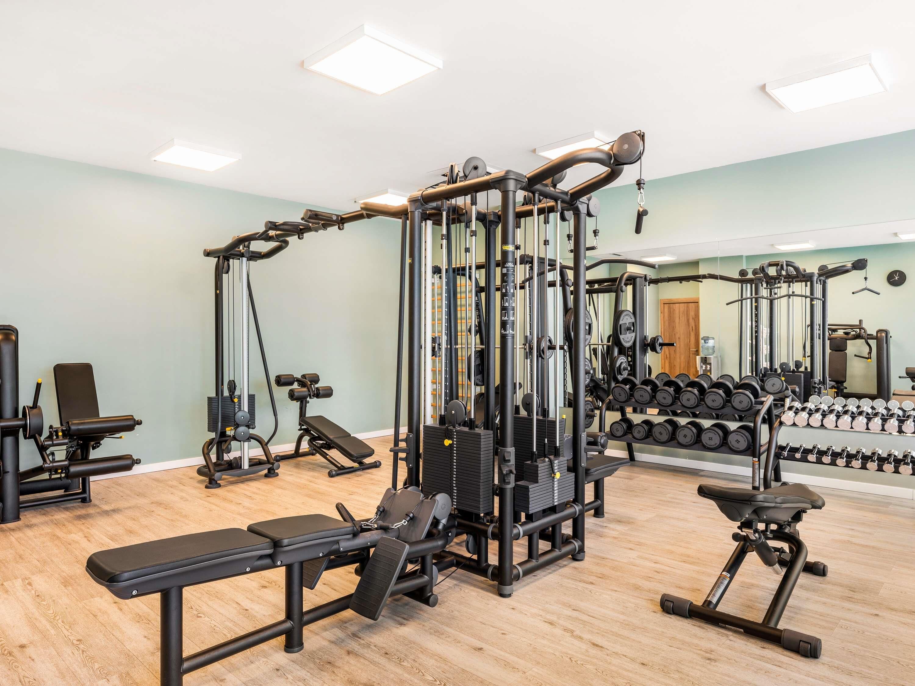 A gym with various exercise equipment, including a bench press, dumbbells, and a squat rack.
