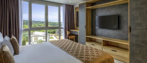Habitación de hotel moderna con una cama grande, un televisor montado en una pared de madera y vistas al campo.