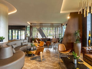 A modern interior with a curved sofa, a round coffee table, and a seating area with chairs and a couch. - Mövenpick Resort and Spa Fruske Terme  (Vrdnik)
