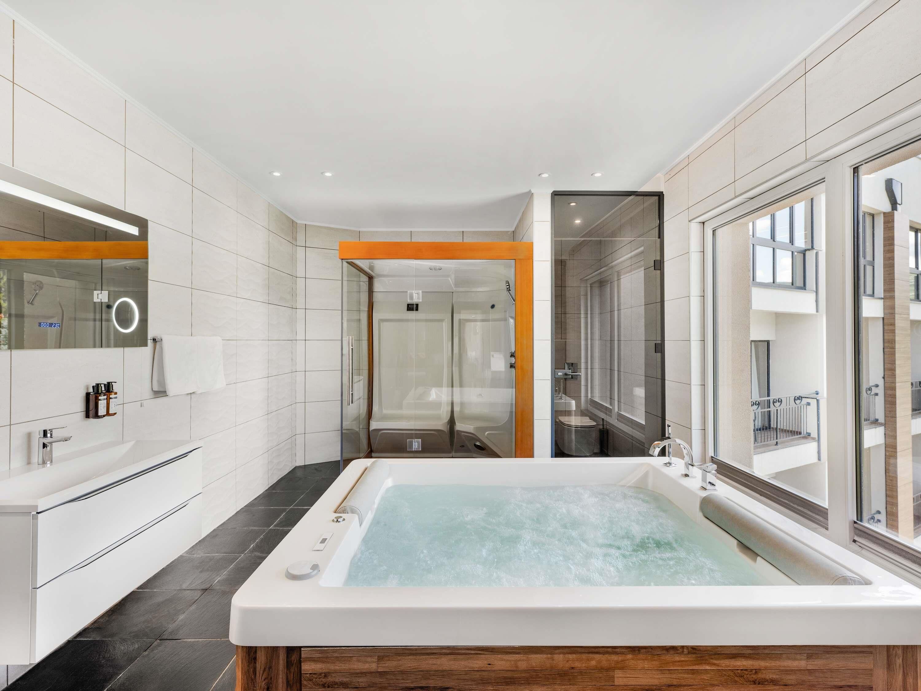Un baño moderno con una bañera grande, una ducha con cerramiento de vidrio y un tocador con espejo.