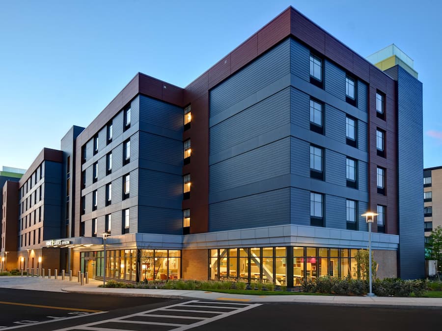 A multi-story hotel with a modern design, featuring a mix of glass and metal facades, and a visible entrance with a well-lit lobby area.