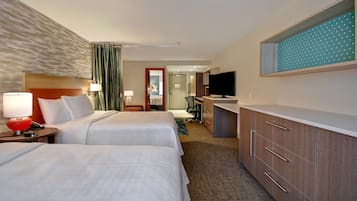 A hotel room with two beds, a desk, a TV, and a bathroom visible through an open door.