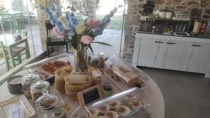 En morgenmadsbuffet med et udvalg af kager, sandwiches og desserter anrettet i gennemsigtige beholdere.