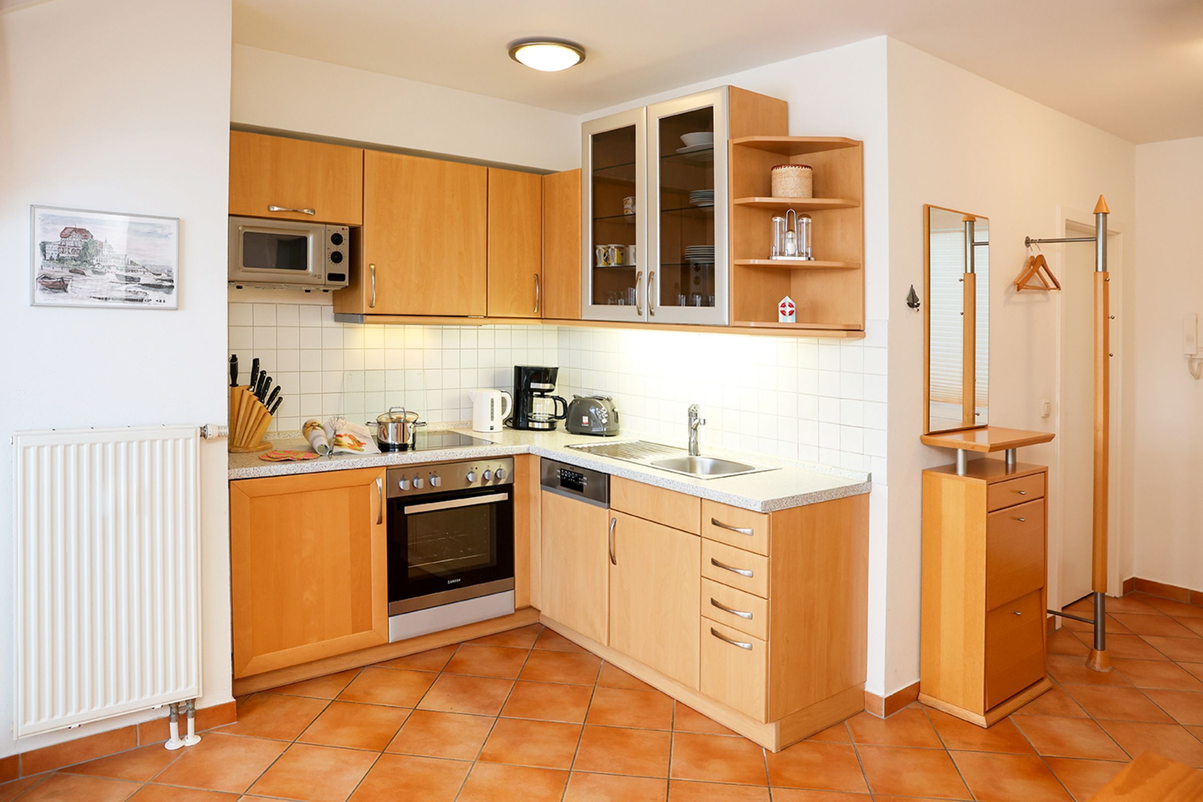 A kitchen with wooden cabinets, a microwave, an oven, a sink, and a coffee maker.
