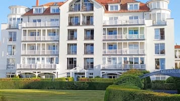 Ein mehrstöckiges Hotel mit Balkonen, einem gepflegten Rasen und blauem Himmel.