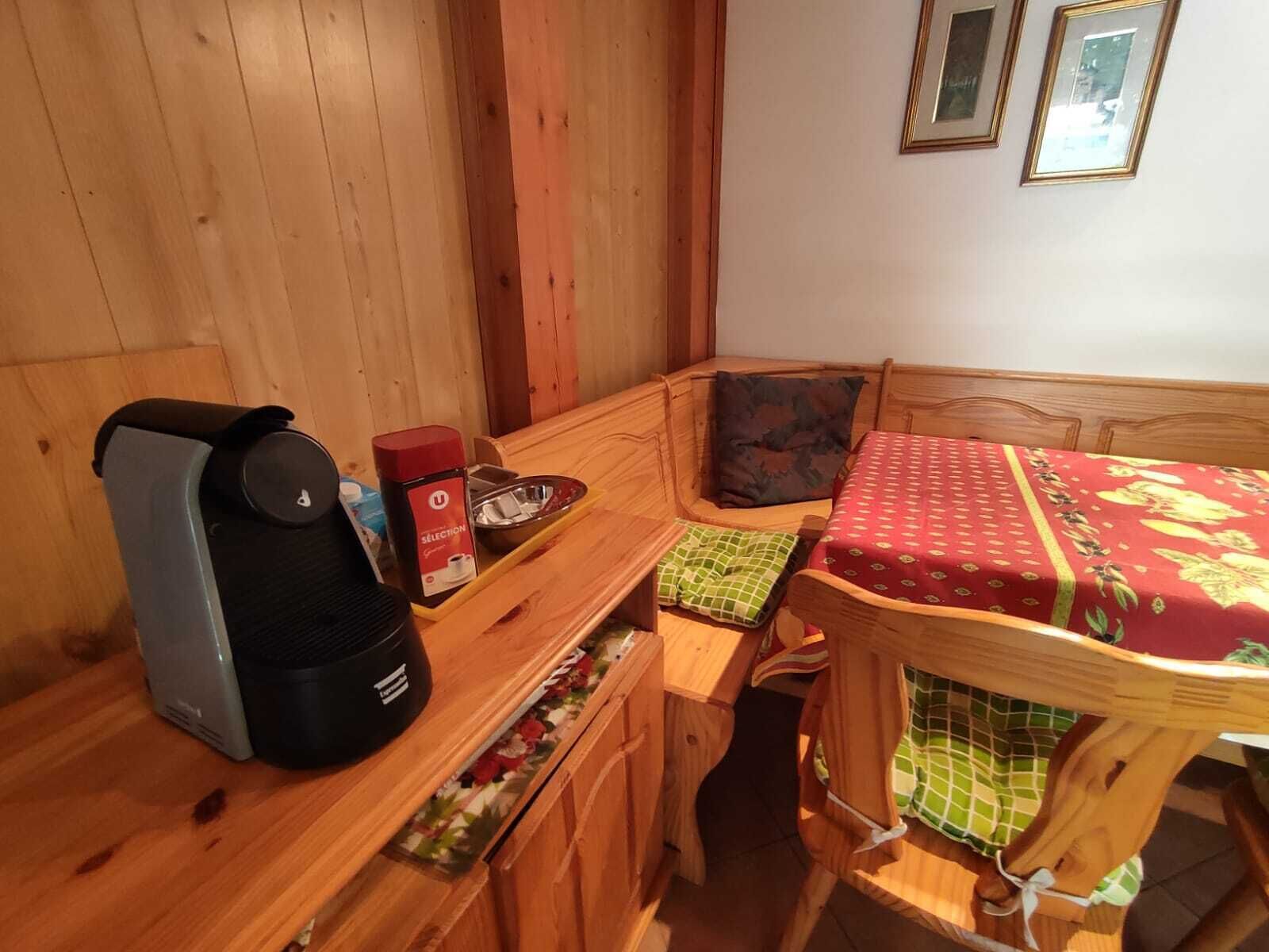 A cozy wooden room with a bed, a small table with a kettle, a cup, and a box.