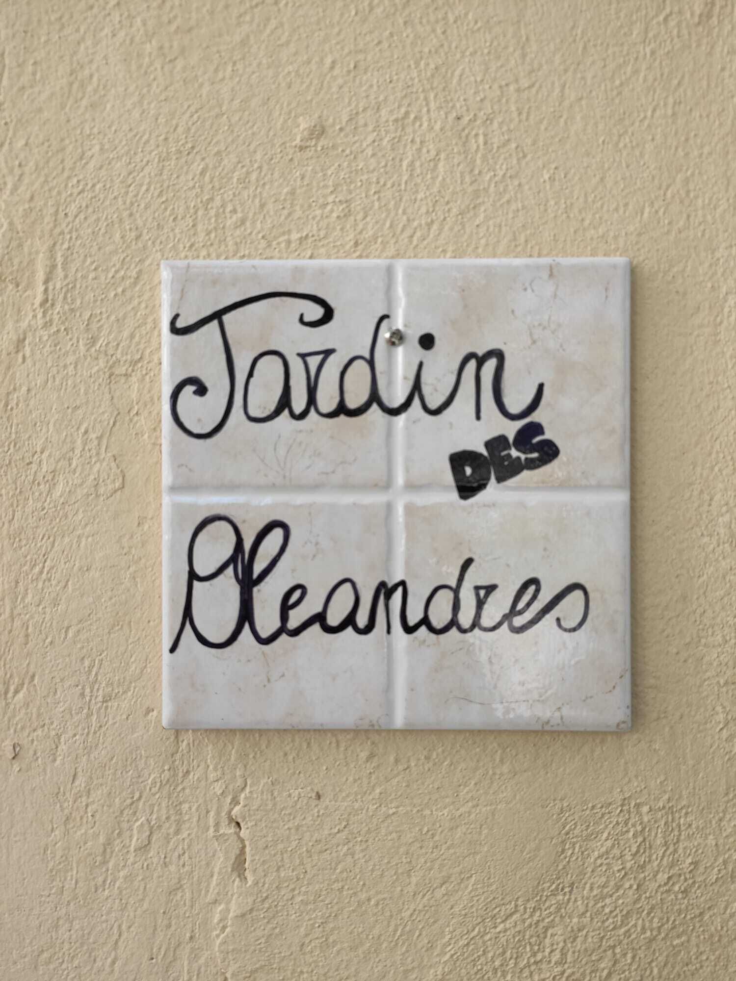 A white tile with black text that reads "Tardin des Bleandes."