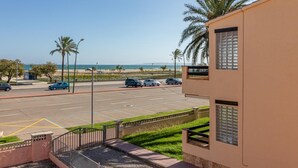 Een parkeerplaats met auto's, een gebouw met een modern design en uitzicht op het strand.