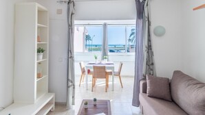 Een moderne woonkamer met balkon, witte muren en uitzicht op het strand.