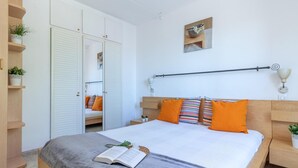 Een slaapkamer met een bed, nachtkastje, kastruimte en een wandplank met planten.