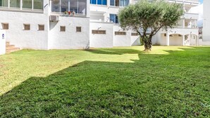 Un edificio residenziale a più piani con balconi, un cortile alberato e un albero.