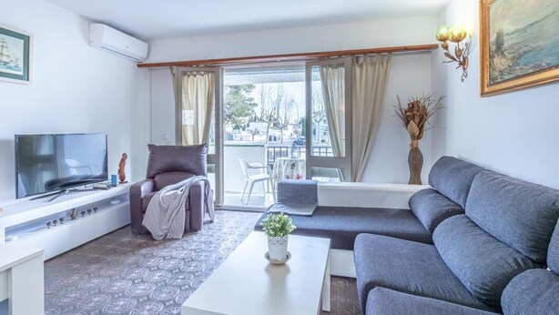 A modern living room with a sofa, a TV, a coffee table, and a balcony with a view of the city. - Fisherman's house, 4 bedrooms, mooring, WIFI, beach very close. (Empuriabrava)