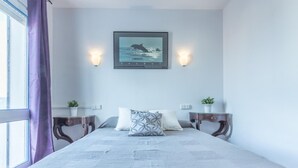 A neatly arranged bedroom with a large bed, two bedside tables with lamps, a framed picture on the wall, and a window with curtains. - Fisherman's house, 4 bedrooms, mooring, WIFI, beach very close. (Empuriabrava)
