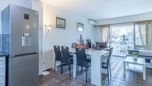 A modern kitchen with a built-in refrigerator, a dining area with a table and chairs, and a living area with a sofa and a window. - Fisherman's house, 4 bedrooms, mooring, WIFI, beach very close. (Empuriabrava)