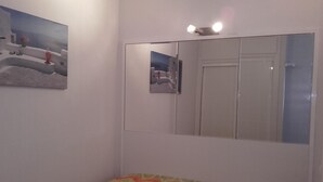 Um quarto com uma cama, um espelho e um quadro na parede.