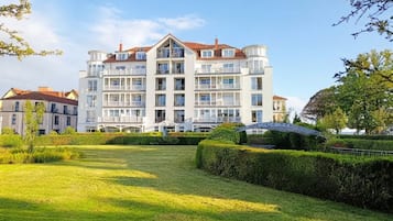 Un hotel de varios pisos con balcones, un césped bien cuidado y un cielo despejado.