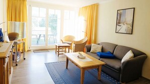 Ein Wohnzimmer mit einer Couch, einem Couchtisch, einem Sessel und einem Essbereich mit einem Servicewagen.