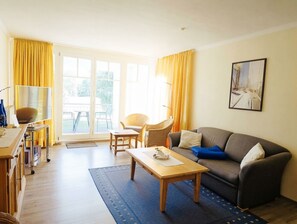 En stue med sofa, sofabord, stol og et spiseområde med en serveringsvogn.