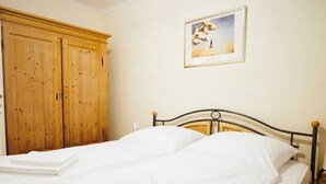 Ein Schlafzimmer mit einem Doppelbett, einem Holzschrank und einem gerahmten Bild an der Wand.