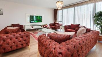 Una sala moderna con un amplio sofá rojo, una mesa de centro de vidrio y un televisor de pantalla plana montado en la pared.