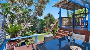 A patio with a glass table, outdoor seating, and a view of tropical vegetation.