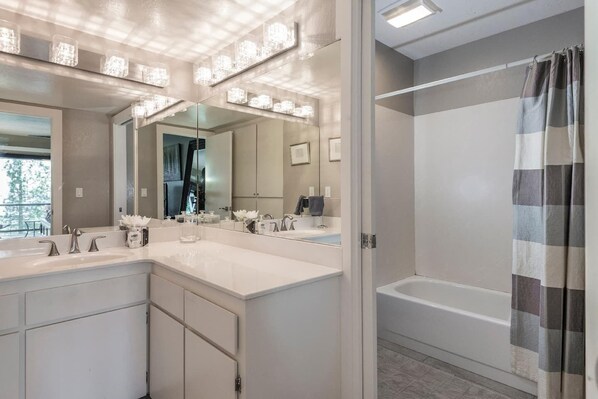Une salle de bain moderne avec un grand meuble-lavabo, une baignoire et un rideau de douche.