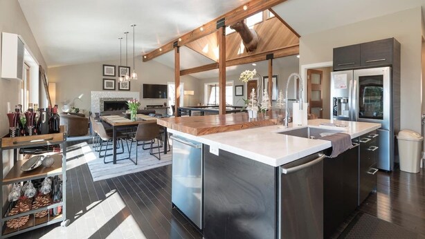 A modern kitchen with a large island, stainless steel appliances, and a dining area with a fireplace. - Skylake Serenity Retreat (Incline Village)
