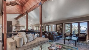 A spacious living area with a large sofa, a glass coffee table, and a view of the kitchen and outdoor space. - Skylake Serenity Retreat (Incline Village)