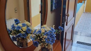 Un couloir avec une console en bois, un miroir et un vase de fleurs.
