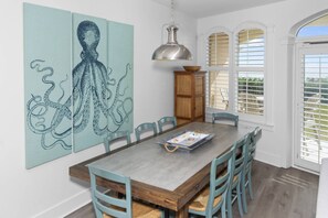Un comedor con una mesa grande, sillas y una lámpara colgante.