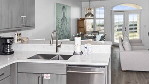 Uma cozinha moderna com uma ilha grande, eletrodomésticos de aço inoxidável e um espaço de refeições com vista.