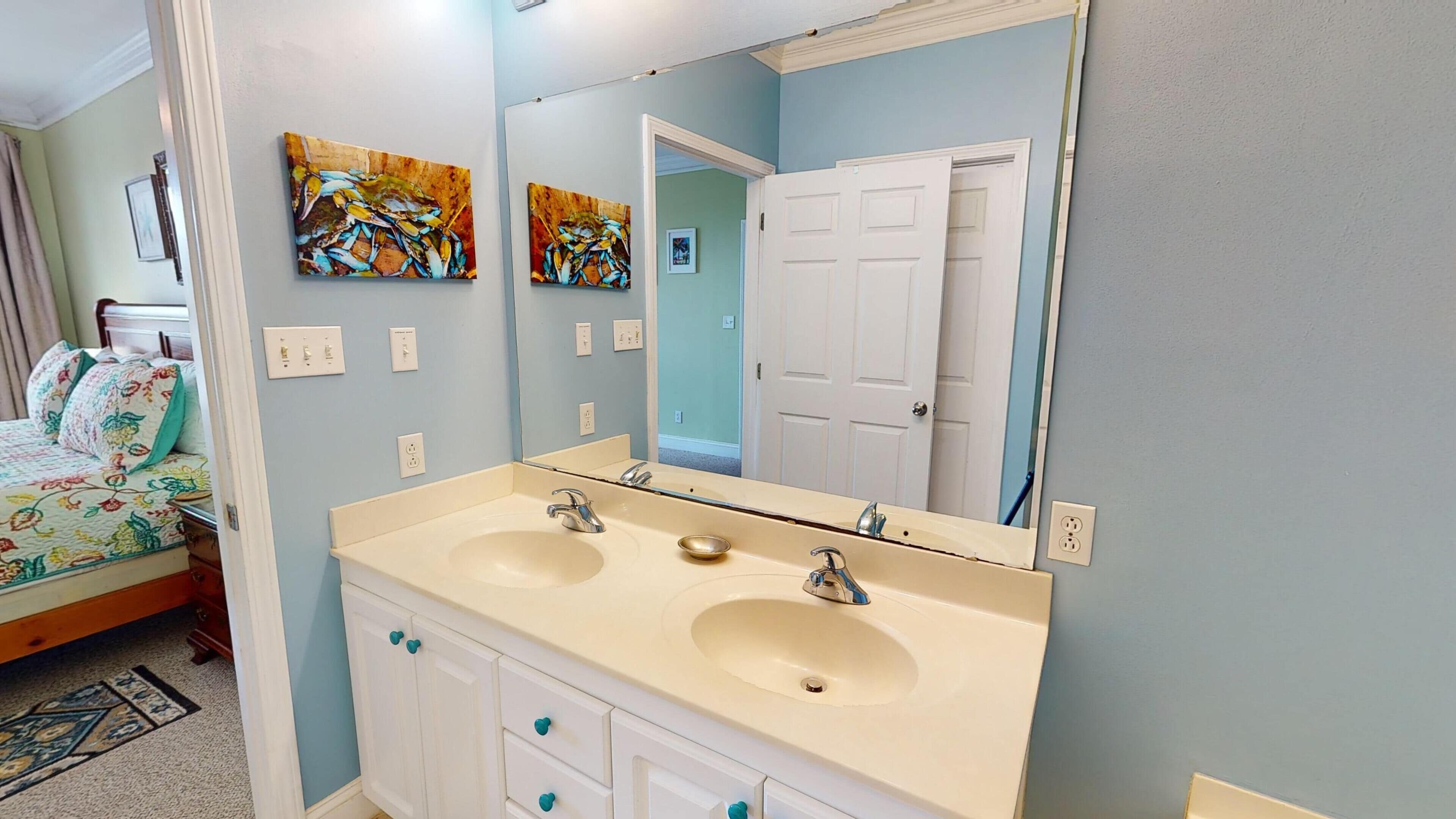 A bathroom with two sinks, a large mirror, and a door leading to another room.