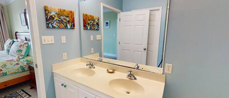 A bathroom with two sinks, a large mirror, and a door leading to another room.