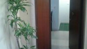 A hallway with a potted plant, a wooden door, and a sign on the wall. - Olimpica Relais Guest House Affittacamere CIR 28624 (Rome)