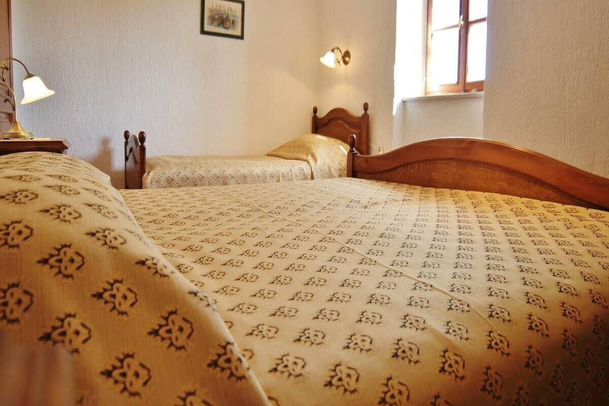 Une chambre avec deux lits, une table de chevet, une lampe et un luminaire fixé au mur.